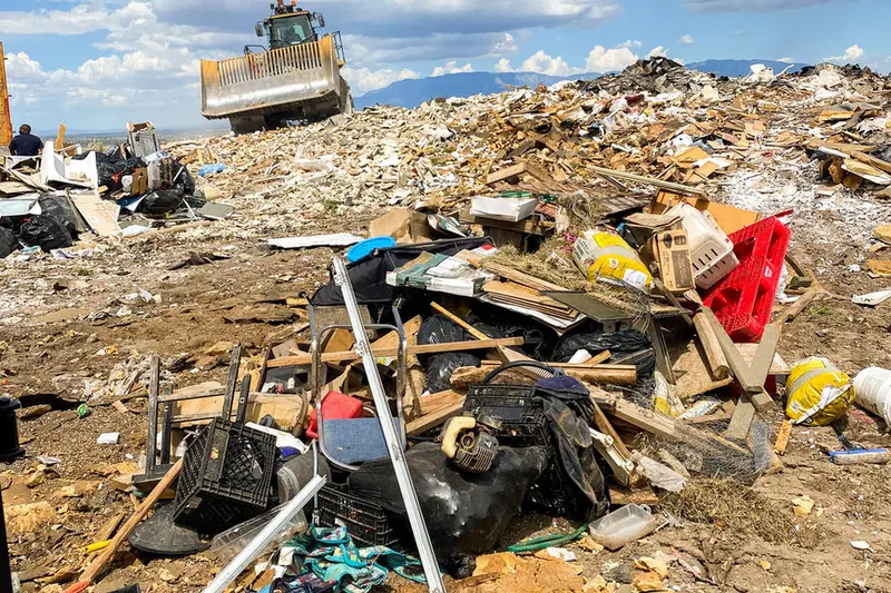 Green dumpster on truck with Sandia Mountains backdrop